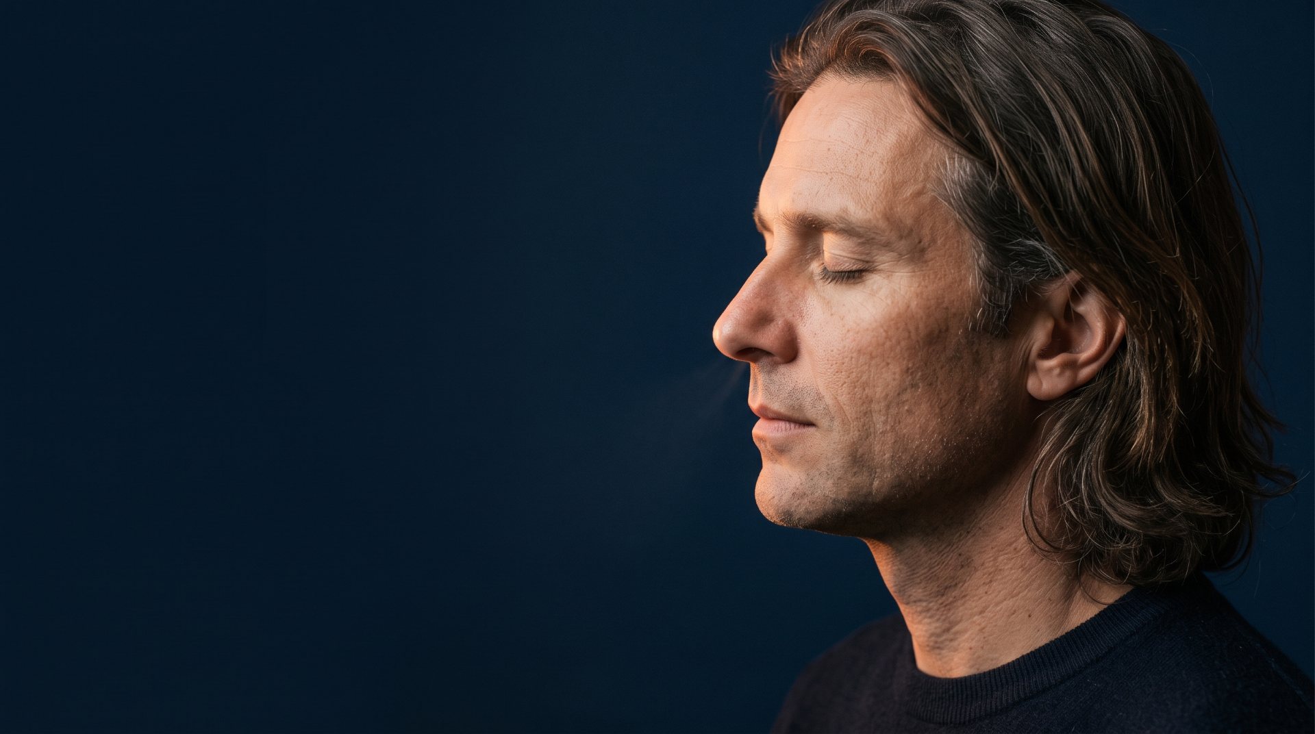 Homme de profil, les yeux fermés, respirant calmement par le nez sur fond bleu nuit